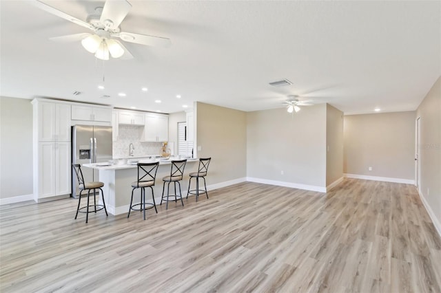 1203 16th Cir SE, Largo, FL 33771 - kitchen with a ceiling fan, stainless steel fridge with ice dispenser, a breakfast bar area, a sink, and tasteful backsplash