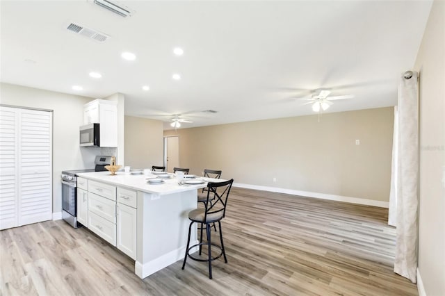 1203 16th Cir SE, Largo, FL 33771 - kitchen featuring stainless steel appliances, ceiling fan, a breakfast bar, white cabinets, and recessed lighting