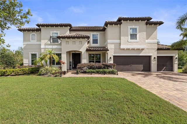 mediterranean / spanish-style house featuring a tiled roof, a front yard, stucco siding, and decorative driveway