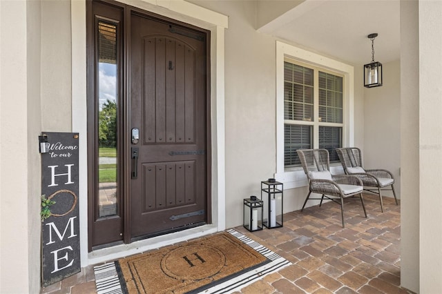 entrance to property featuring a porch and stucco siding