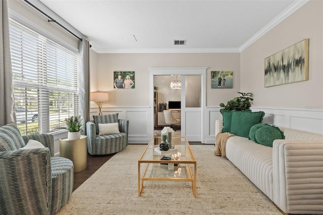 living area featuring ornamental molding, visible vents, a notable chandelier, and wood finished floors