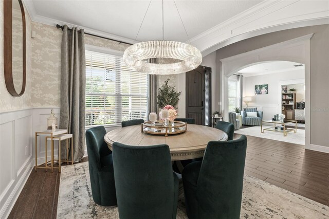 dining area featuring a chandelier, arched walkways, wainscoting, and wood finished floors
