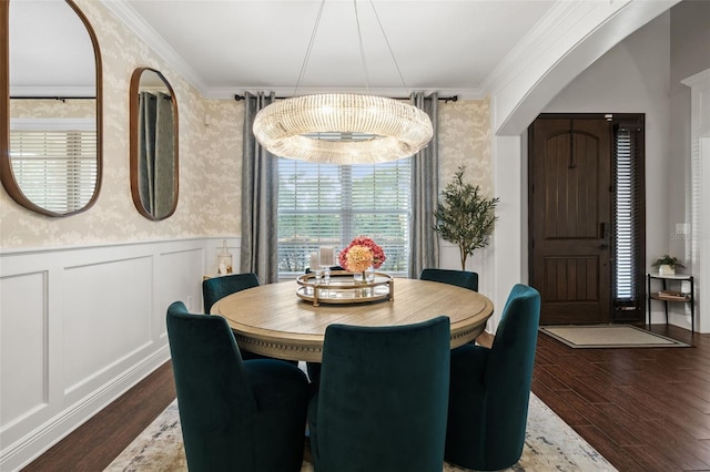 dining area with crown molding, wallpapered walls, wood finished floors, and a wainscoted wall