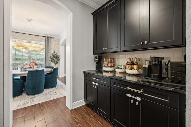 bar with tasteful backsplash, ornamental molding, wood tiled floor, and arched walkways