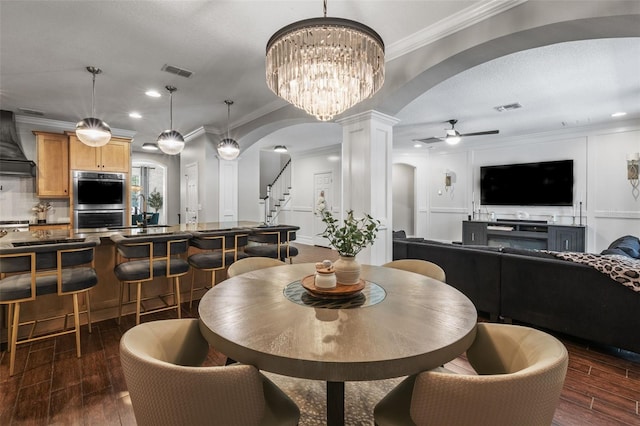 dining area with decorative columns, arched walkways, visible vents, and ceiling fan with notable chandelier