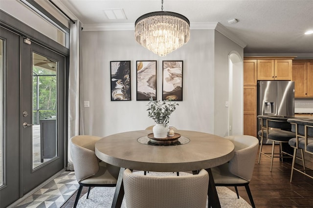 dining area featuring ornamental molding, a notable chandelier, visible vents, and dark wood finished floors