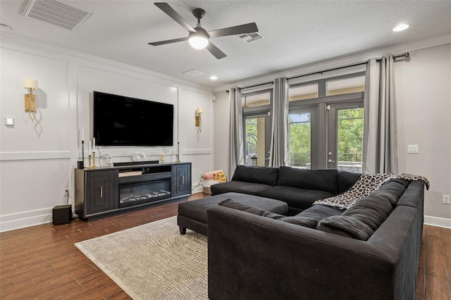 living area with visible vents, ceiling fan, crown molding, and dark wood-style floors