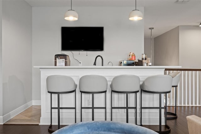 bar with dark wood-style flooring, baseboards, visible vents, and hanging light fixtures
