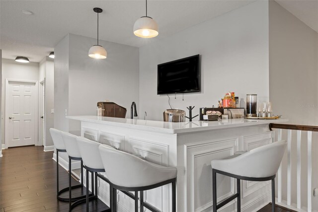 bar with hanging light fixtures, baseboards, and dark wood-style floors