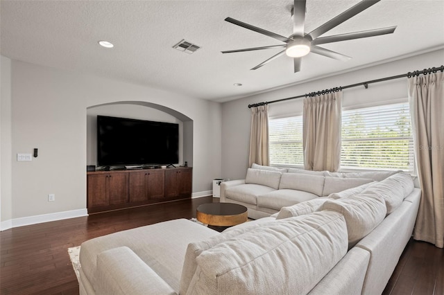 living room with a textured ceiling, dark wood finished floors, baseboards, and a ceiling fan