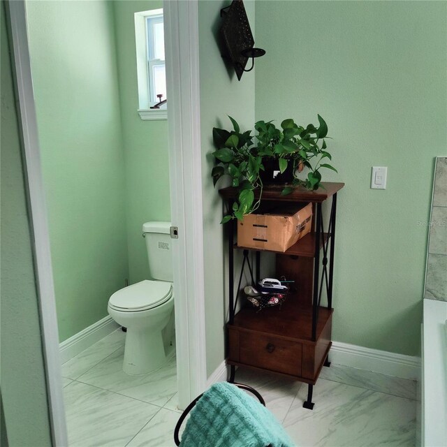 6690 54th Ave N, Saint Petersburg, FL 33709 - bathroom with toilet, baseboards, and marble finish floor