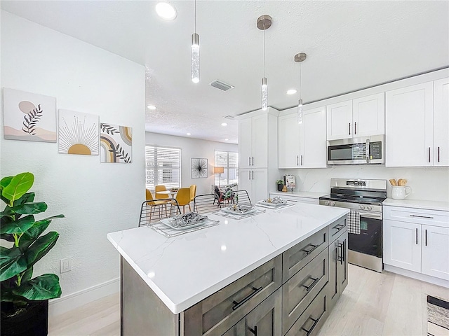 2711 W Cordelia St, Tampa, FL 33607 - kitchen featuring visible vents, a center island, light wood-type flooring, white cabinetry, and stainless steel appliances
