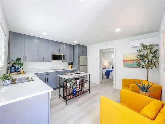 2711 W Cordelia St, Tampa, FL 33607 - kitchen featuring a sink, an AC wall unit, light countertops, appliances with stainless steel finishes, and light wood-type flooring
