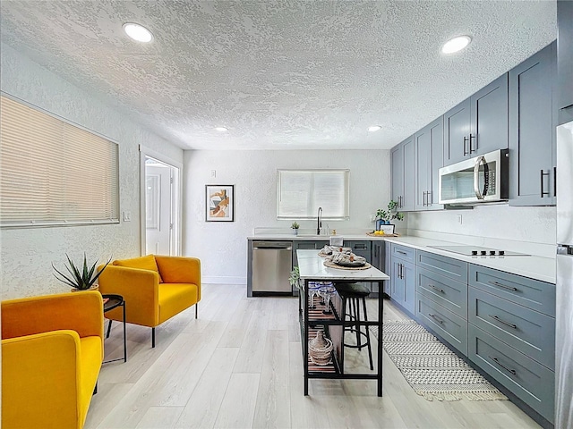 2711 W Cordelia St, Tampa, FL 33607 - kitchen with gray cabinets, a textured wall, a textured ceiling, stainless steel appliances, and light wood finished floors