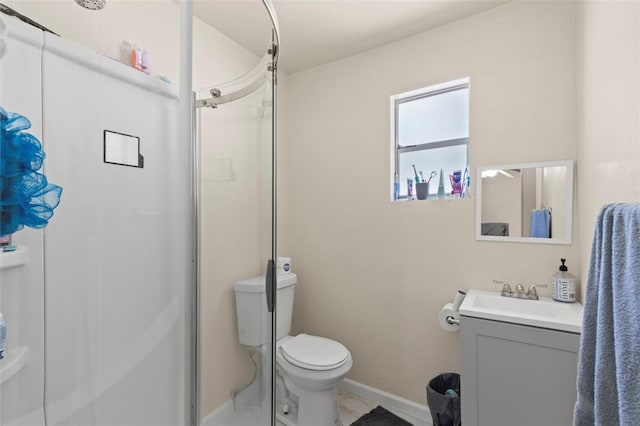 bathroom featuring toilet, vanity, a stall shower, and baseboards