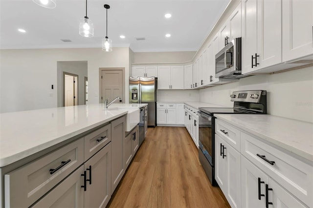 kitchen featuring light countertops, ornamental molding, a sink, hanging light fixtures, and appliances with stainless steel finishes