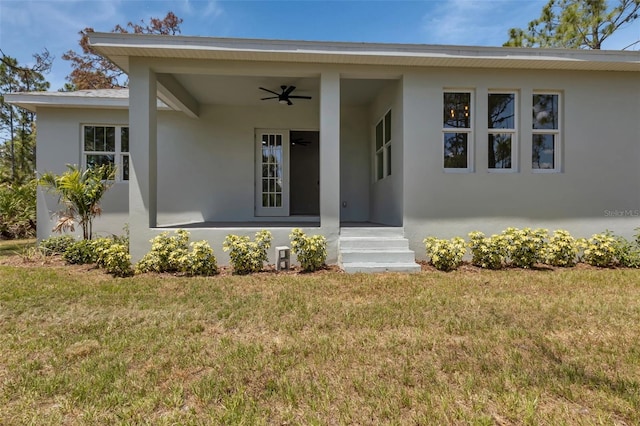 view of front of home featuring stucco siding, a ceiling fan, and a front yard