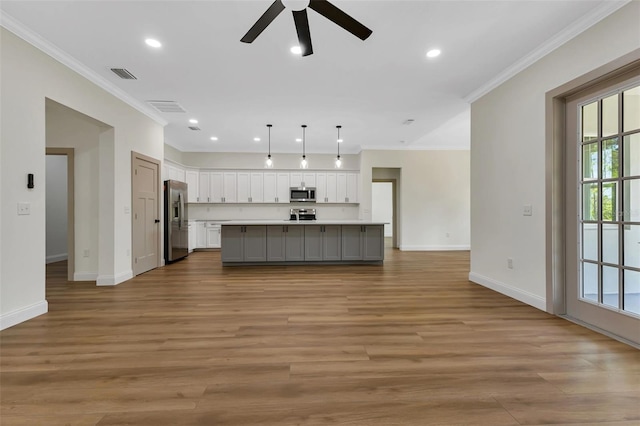 unfurnished living room with visible vents, crown molding, baseboards, and ceiling fan
