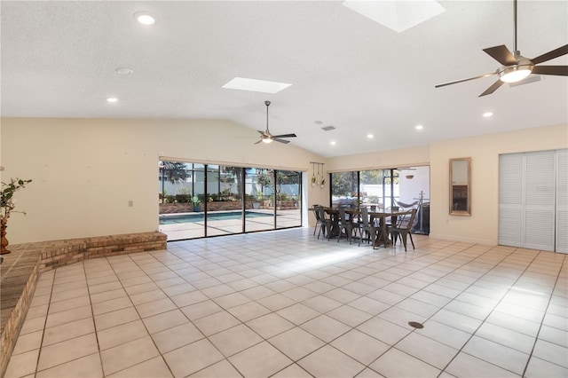 dining area with ceiling fan, a textured ceiling, light tile patterned floors, lofted ceiling with skylight, and recessed lighting