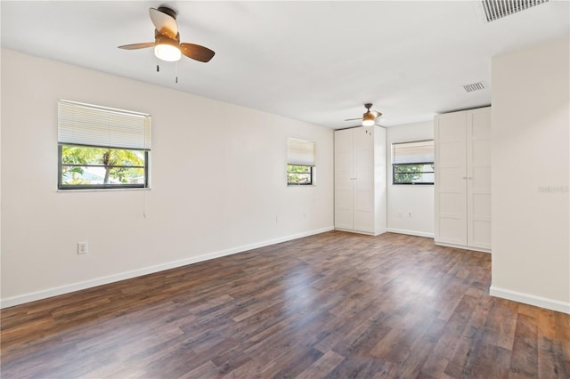 unfurnished room featuring visible vents, dark wood-style flooring, and ceiling fan