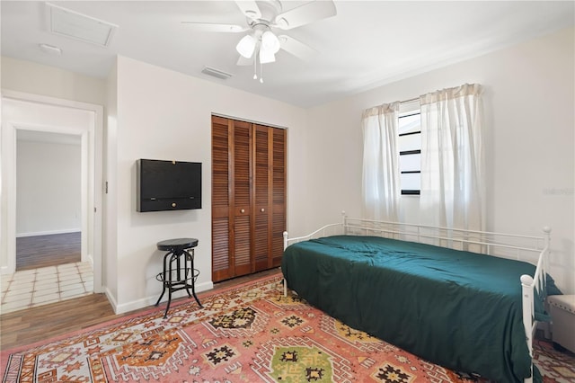 bedroom with a closet, attic access, wood finished floors, and visible vents