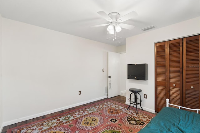 bedroom with baseboards, visible vents, wood finished floors, and a closet