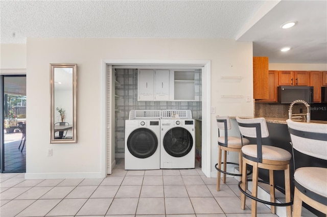 washroom featuring light tile patterned floors, a textured ceiling, cabinet space, and washer and dryer
