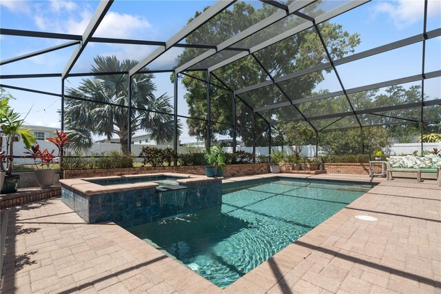 view of swimming pool featuring glass enclosure, a pool with connected hot tub, and a patio area