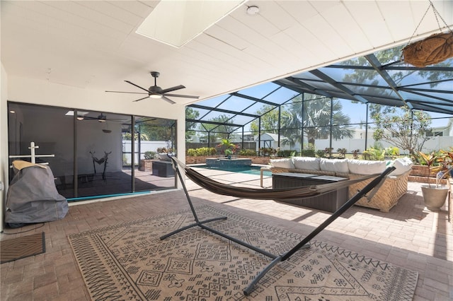 view of patio featuring glass enclosure, a pool with connected hot tub, an outdoor living space, and a ceiling fan