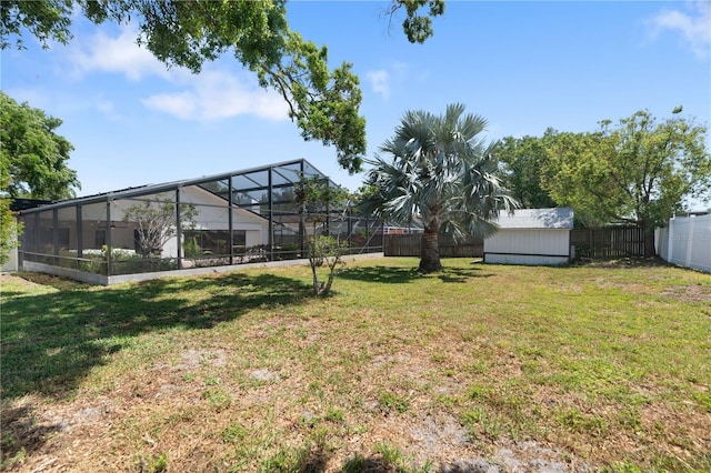 view of yard featuring a fenced backyard, an outbuilding, glass enclosure, and a storage shed