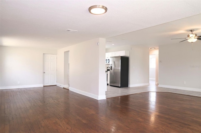 unfurnished living room with wood finished floors, ceiling fan, and baseboards