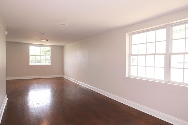 spare room with baseboards, dark wood-style floors, and visible vents