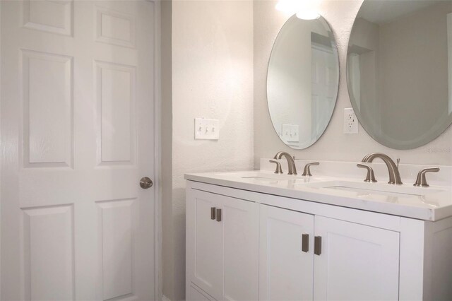 bathroom featuring a sink, double vanity, and a textured wall