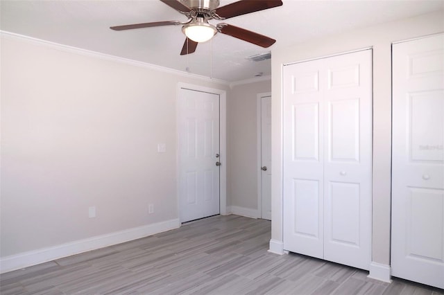 unfurnished bedroom featuring baseboards, light wood-type flooring, crown molding, a ceiling fan, and visible vents