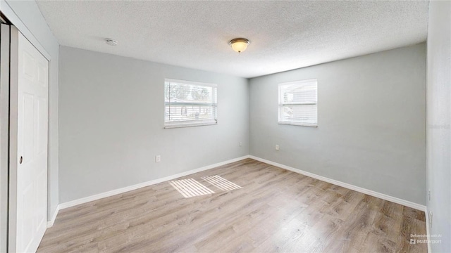 unfurnished bedroom with baseboards, a closet, light wood-style floors, and a textured ceiling