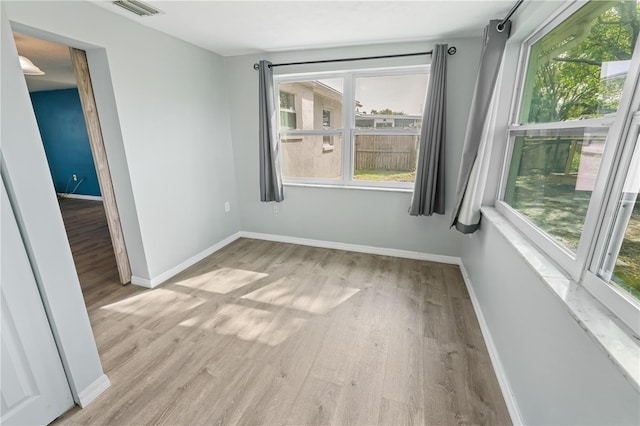 empty room with a wealth of natural light, wood finished floors, and baseboards