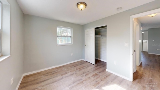 unfurnished bedroom featuring baseboards, a closet, and wood finished floors