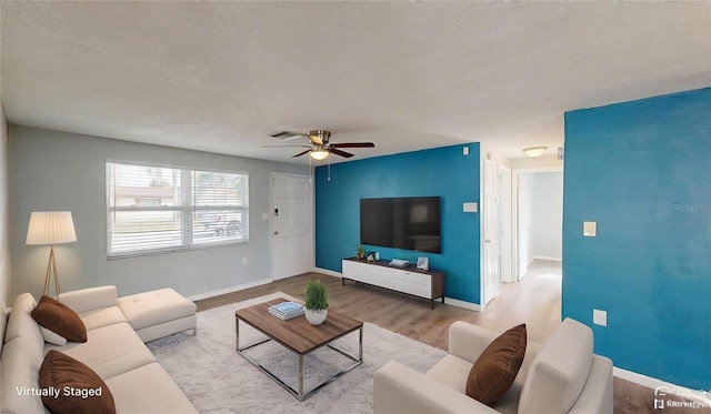 living area featuring baseboards, visible vents, wood finished floors, and ceiling fan