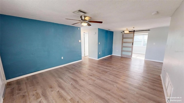 spare room with baseboards, ceiling fan, visible vents, and wood finished floors