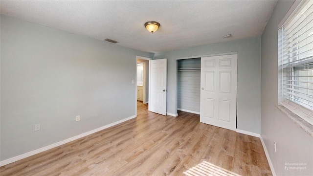 unfurnished bedroom with baseboards, visible vents, a closet, and light wood finished floors