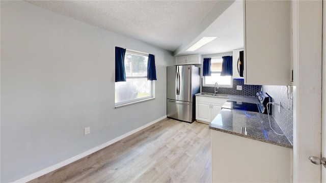 kitchen featuring range, light wood finished floors, baseboards, backsplash, and freestanding refrigerator