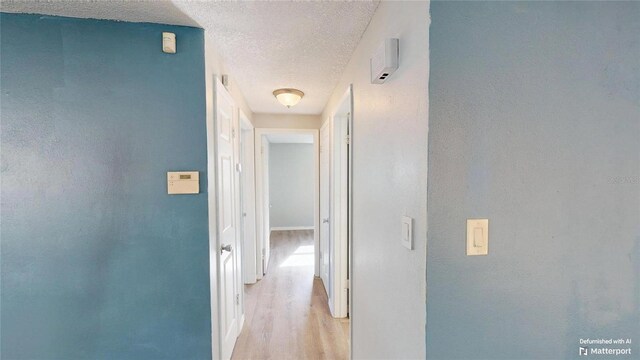 hall featuring light wood finished floors and a textured ceiling