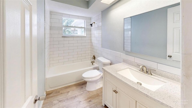 full bath with tile walls, bathtub / shower combination, wood finished floors, toilet, and vanity