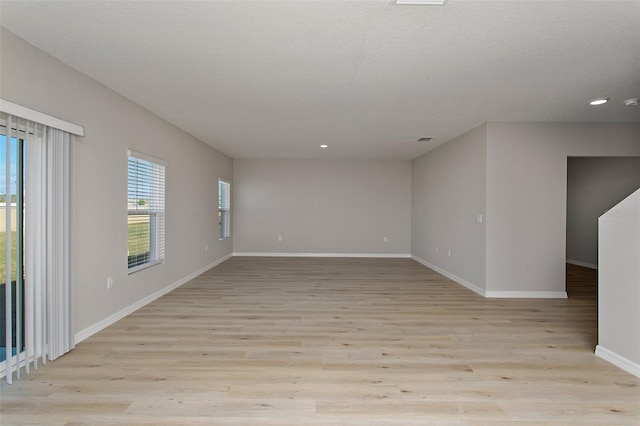 spare room featuring baseboards, recessed lighting, and light wood-type flooring