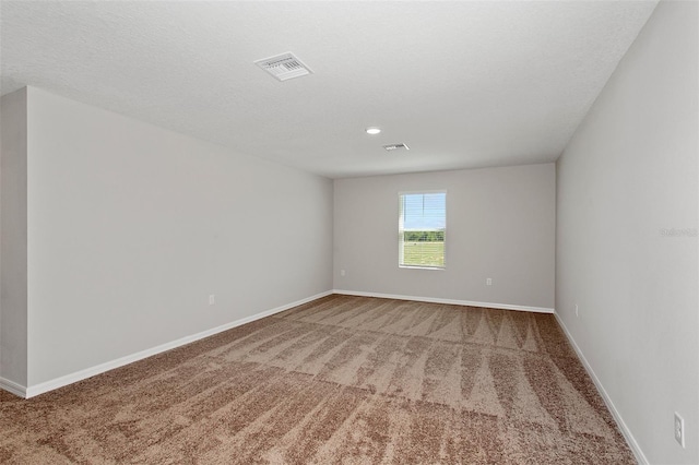 empty room featuring baseboards, a textured ceiling, visible vents, and carpet