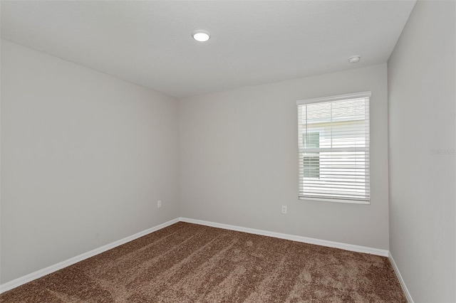 empty room featuring baseboards and dark carpet