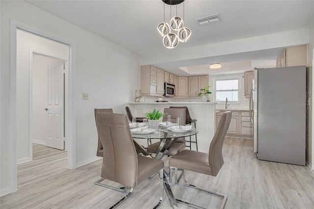 7906 Bayshore Dr, Seminole, FL 33776 - dining room featuring visible vents, baseboards, light wood-type flooring, and a textured ceiling