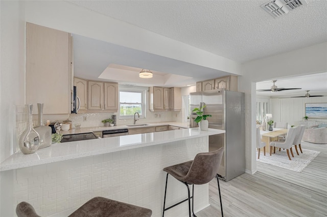 7906 Bayshore Dr, Seminole, FL 33776 - kitchen featuring a tray ceiling, light countertops, light brown cabinetry, and appliances with stainless steel finishes