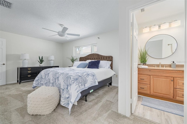 7906 Bayshore Dr, Seminole, FL 33776 - bedroom with visible vents, connected bathroom, light colored carpet, and a textured ceiling