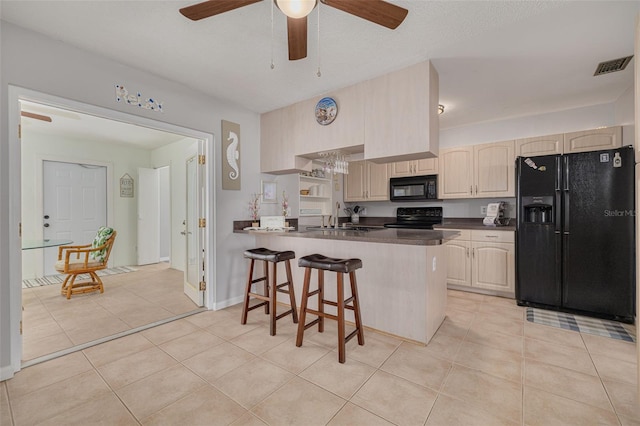 2605 Fulton St SW, Largo, FL 33774 - kitchen featuring black appliances, a sink, dark countertops, a breakfast bar area, and a peninsula